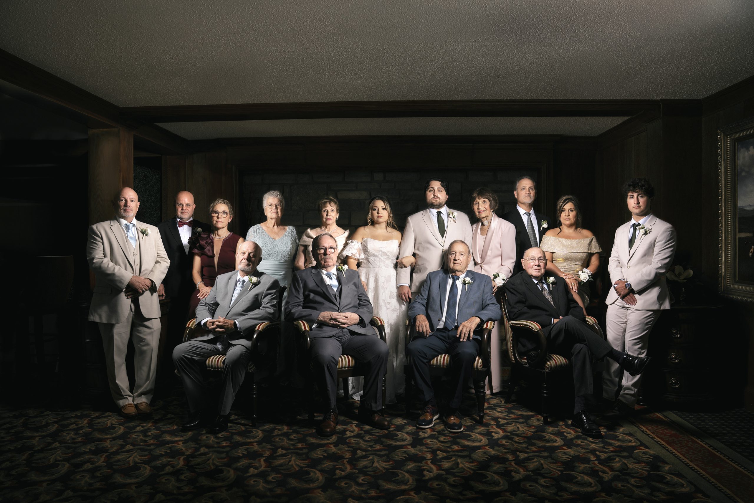 Formal wedding family portrait with bride, groom, and extended family members in elegant lighting