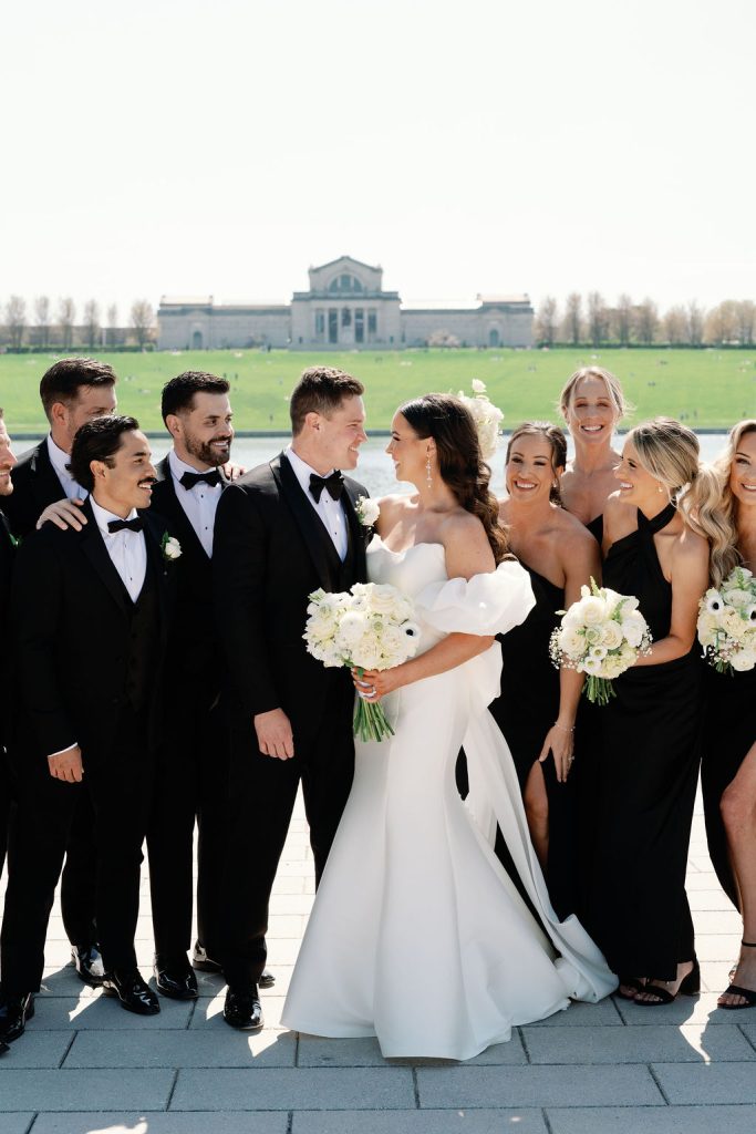 Wedding party in black and white attire at St. Louis Art Museum with bride and groom embracing