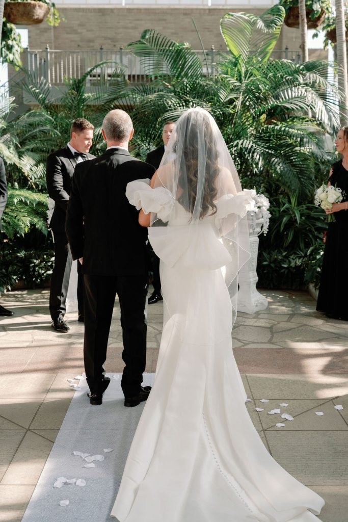 Wedding ceremony with bride and groom exchanging vows before tropical palm backdrop