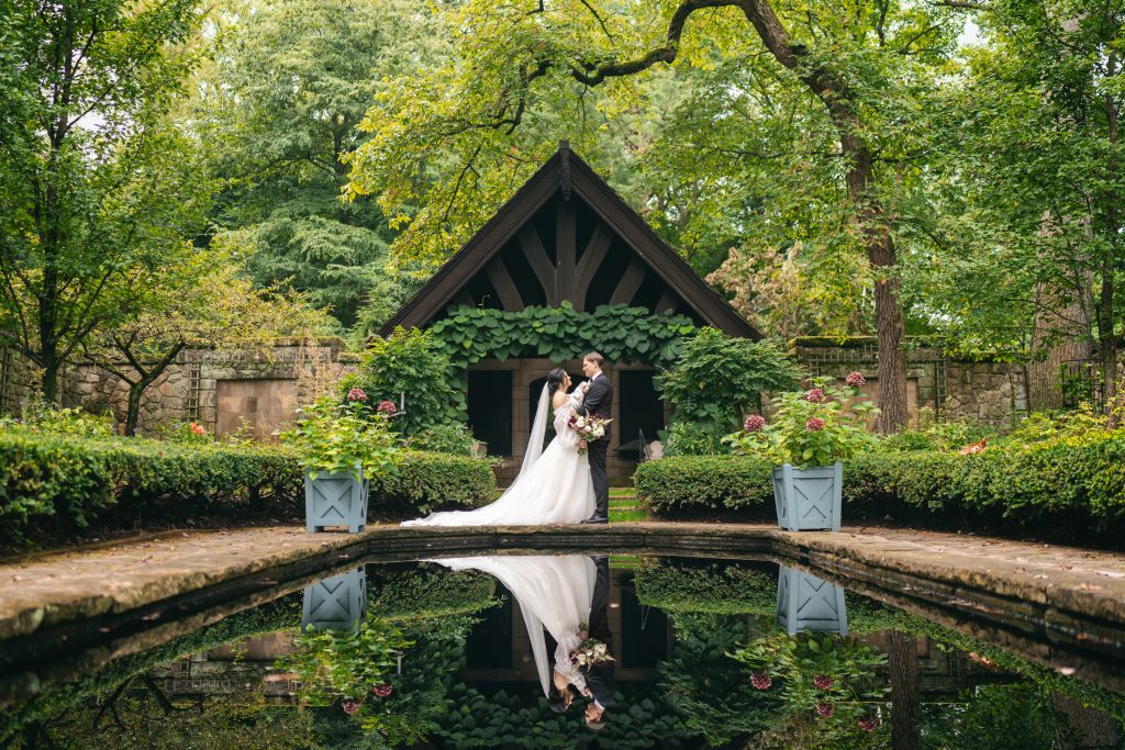 Bride and groom embracing under black pavilion beside reflecting pool