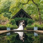 Bride and groom embracing under black pavilion beside reflecting pool