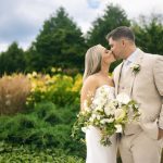 Couple sharing intimate moment in garden setting with white floral bouquet