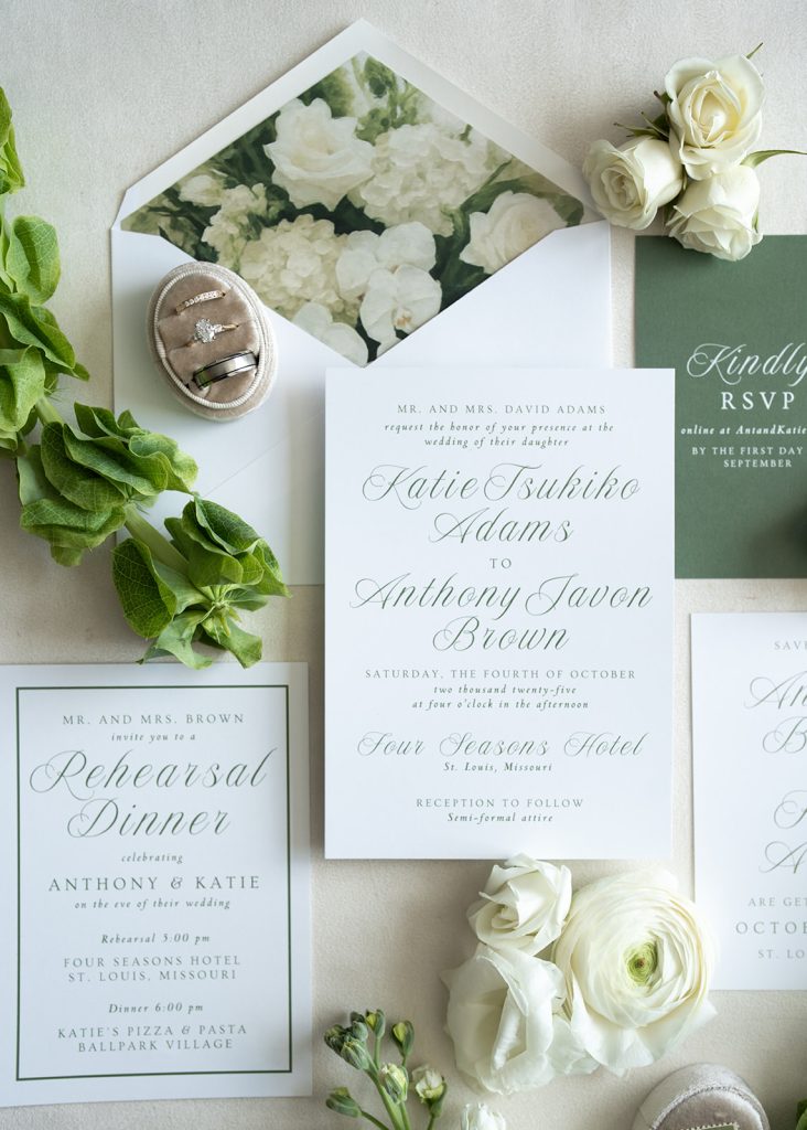 Katie and Anthony's wedding invitation suite with white roses, rings, and sage green floral envelope liner