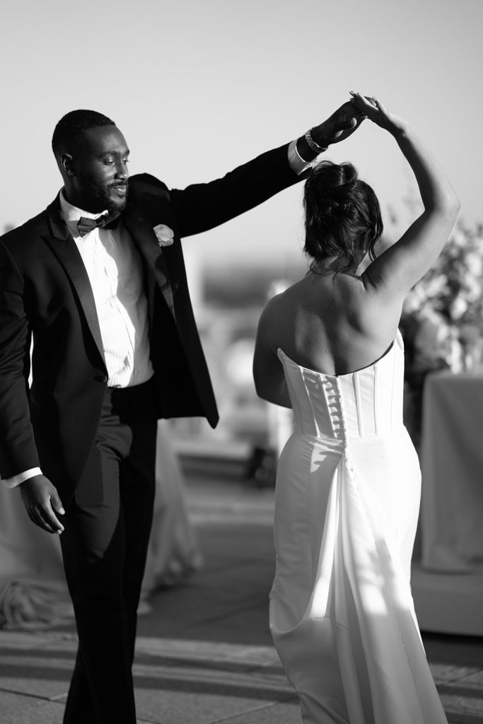 Anthony twirling Katie during their first dance on a rooftop, black and white photograph