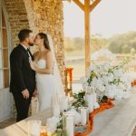Romantic outdoor wedding ceremony featuring white orchid arrangements, greenery, and candlelight on terrace