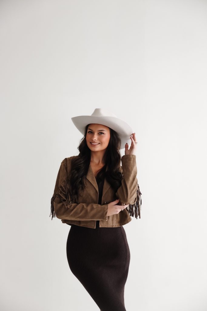 Wedding photographer in white cowboy hat and tan fringe jacket with western-inspired styling