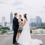 Bride and groom embracing on rooftop terrace with Atlanta city skyline in background