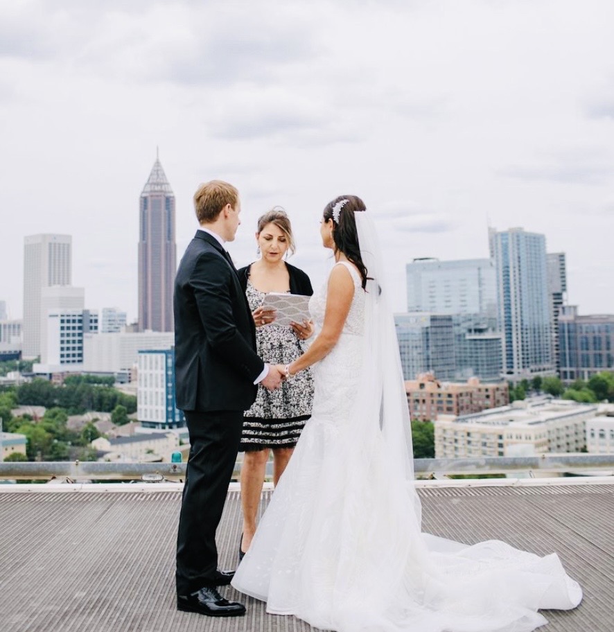 Bride and groom embracing on rooftop terrace with Atlanta city skyline in background