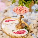 Traditional Persian Sofreh Aghd display with gold tiered stands, decorated sweets, and pink floral accents