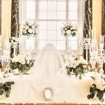 Elegant Sofreh Aghd setup with white draping, tall candelabras, and ivory floral arrangements