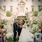 Persian wedding ceremony at grand estate with lush greenery, white floral displays, and seated guests