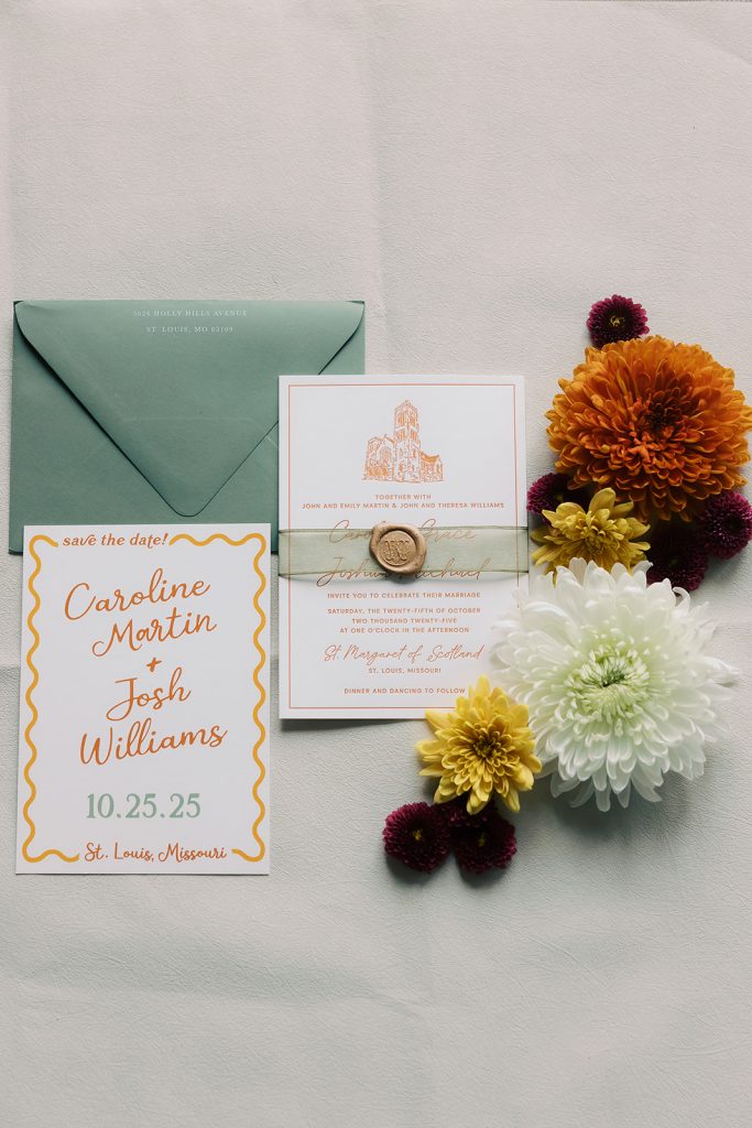 Wedding invitation suite with sage green envelope and orange dahlias, displaying Caroline and Josh's October 25 St. Louis wedding details