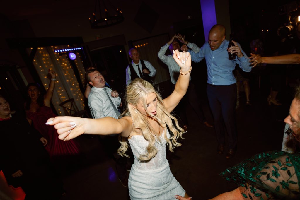 Bride dancing joyfully with arms outstretched at wedding reception celebration