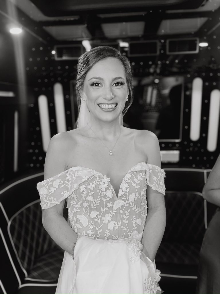 Bride in off the shoulder wedding gown standing inside a Delaware Limo Party Bus at her wedding.