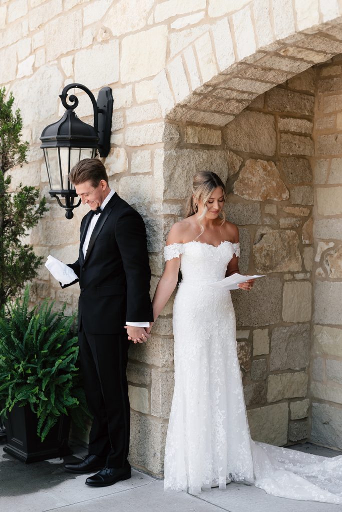 Couple holding hands around stone corner during first look, reading handwritten letters