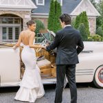 Bride and groom walking toward vintage car