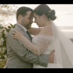 Newlyweds in intimate embrace with white floral bouquet and scenic overlook backdrop
