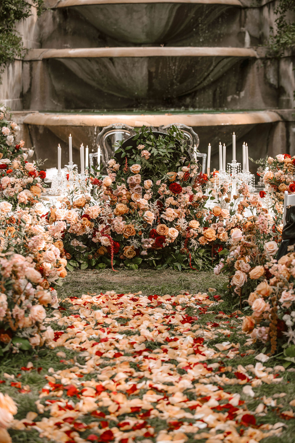 Persian wedding ceremony backdrop with lush blush and peach floral arrangements and rose petal scatter