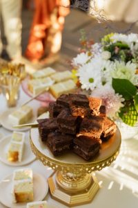 Stacked chocolate brownies displayed on gold pedestal stand at wedding reception