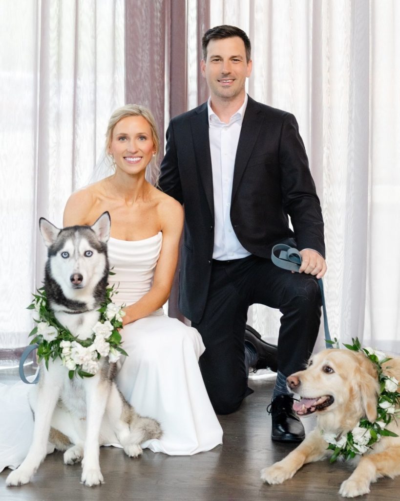 Bride and groom pose with their two dogs wearing floral collars at Highline Car House