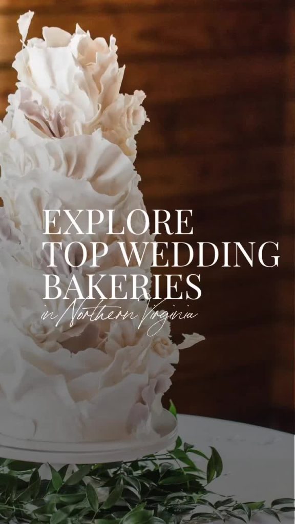 Elegant white textured wedding cake with ruffled fondant details surrounded by greenery