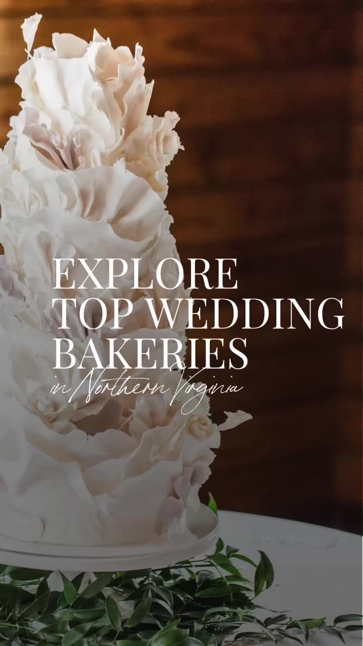 Elegant white textured wedding cake with ruffled fondant details surrounded by greenery