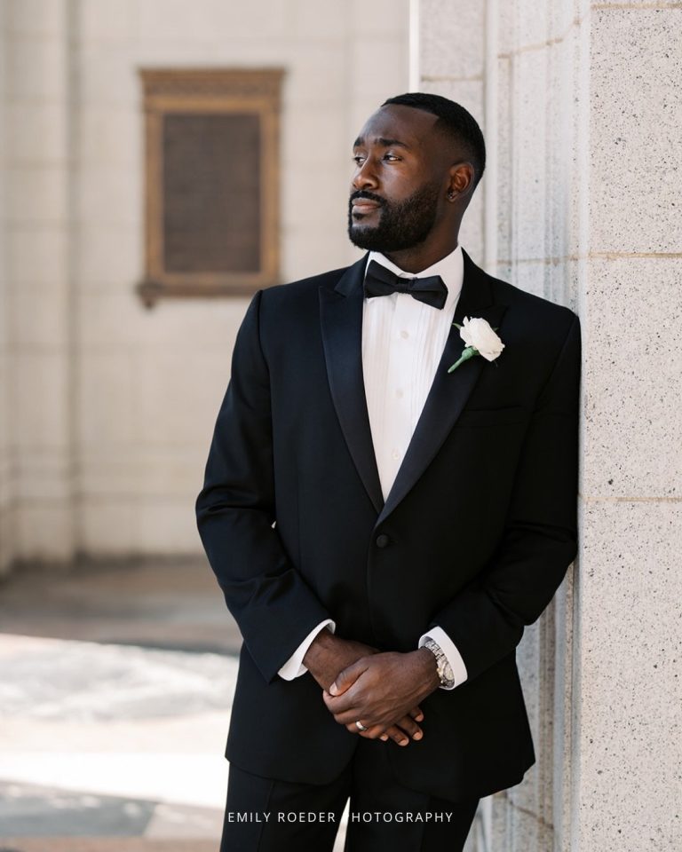 Groom in classic black tuxedo with bow tie and white rose boutonniere