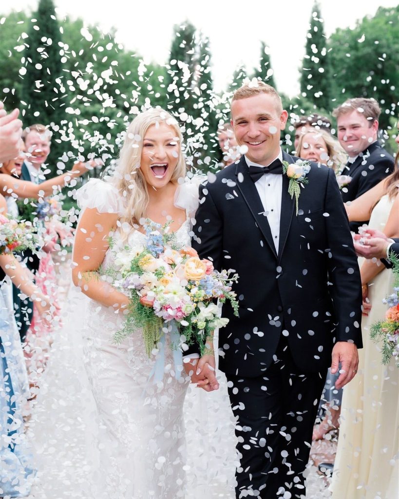 Newlyweds celebrating recessional as guests toss confetti during outdoor Nebraska wedding ceremony