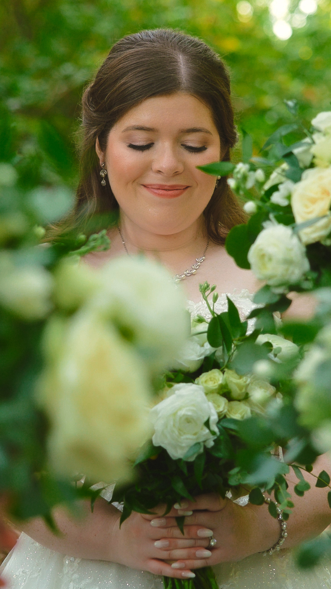 Bride holding white rose bouquet with soft smile, showcasing wedding videography by Ben Schnell Productions