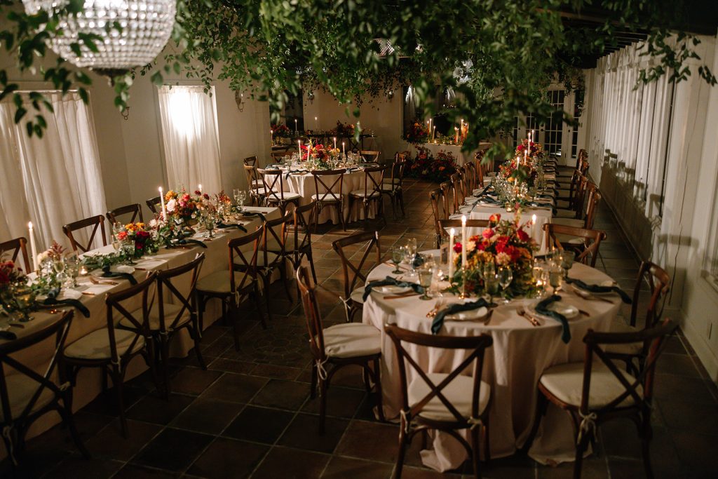 fall moody indoor wedding reception area with hanging wisteria and warm color florals on tables