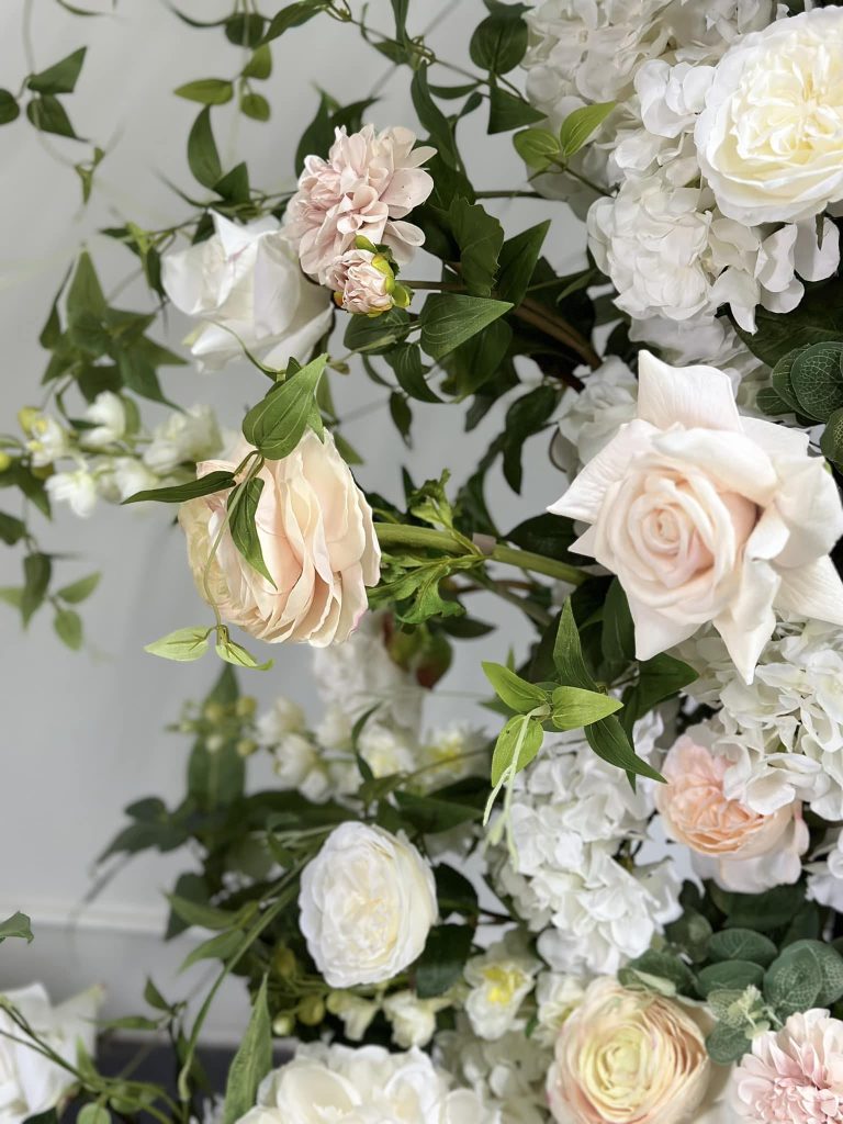 Romantic floral arrangement featuring white and blush roses with hydrangeas and trailing greenery