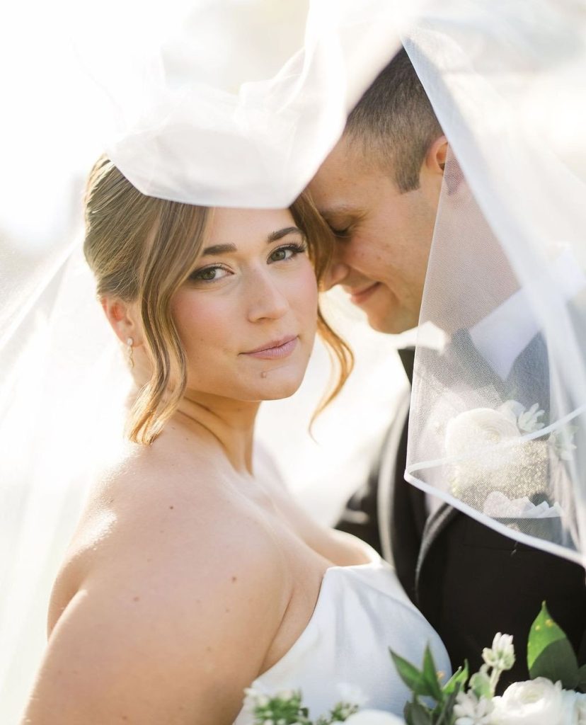 McKenzie and Michael embrace under her flowing veil in an intimate outdoor wedding portrait