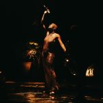 Bride holding dramatic cascading bouquet illuminated against dark background