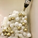 Champagne bottle nestled in white and gold balloon arrangement for wedding celebration