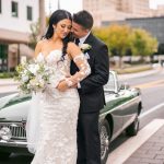 Bride and groom share intimate moment beside vintage green convertible