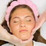 Bride receiving facial massage treatment with pink headband in spa