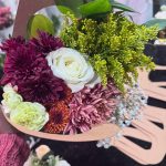 Handcrafted wedding bouquet with burgundy, white, and green flowers in rustic kraft paper holder