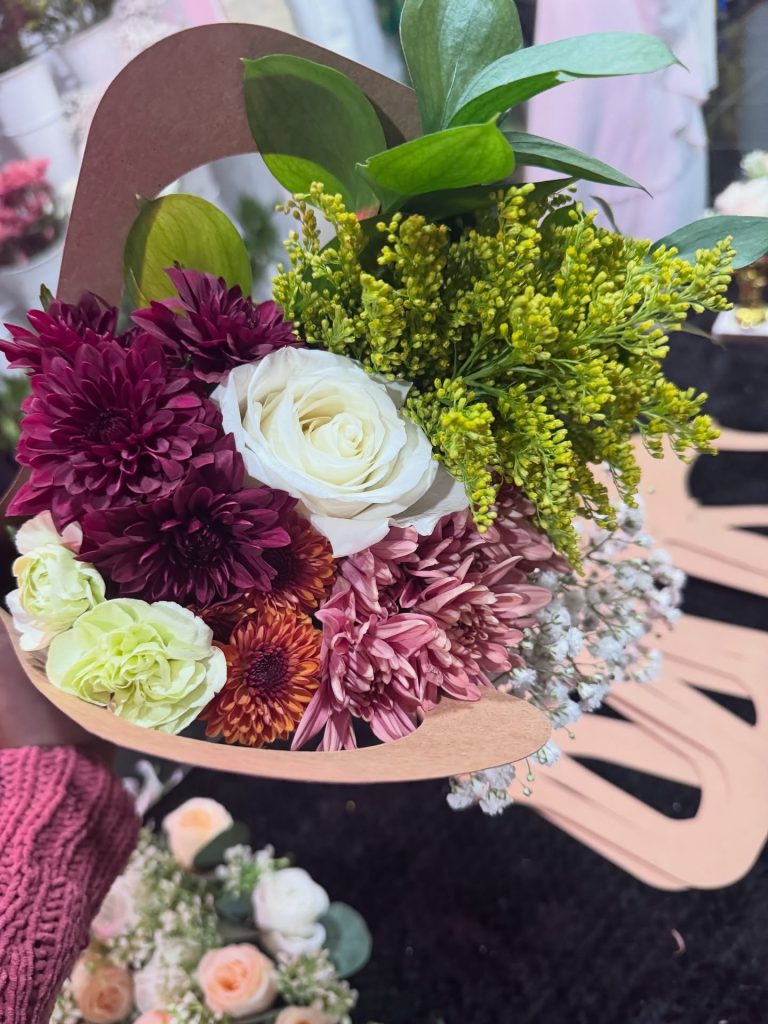 Handcrafted wedding bouquet with burgundy, white, and green flowers in rustic kraft paper holder