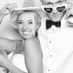 Black and white photo booth portrait of bride and groom with "Mr." and "King" sunglasses
