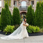 Bride in flowing veil posing at elegant estate with manicured landscaping