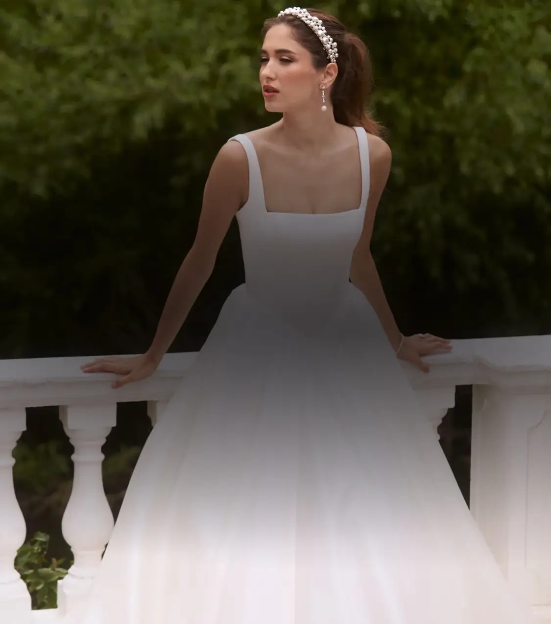 Bride in minimalist square-neck ballgown with flowing tulle skirt against garden backdrop