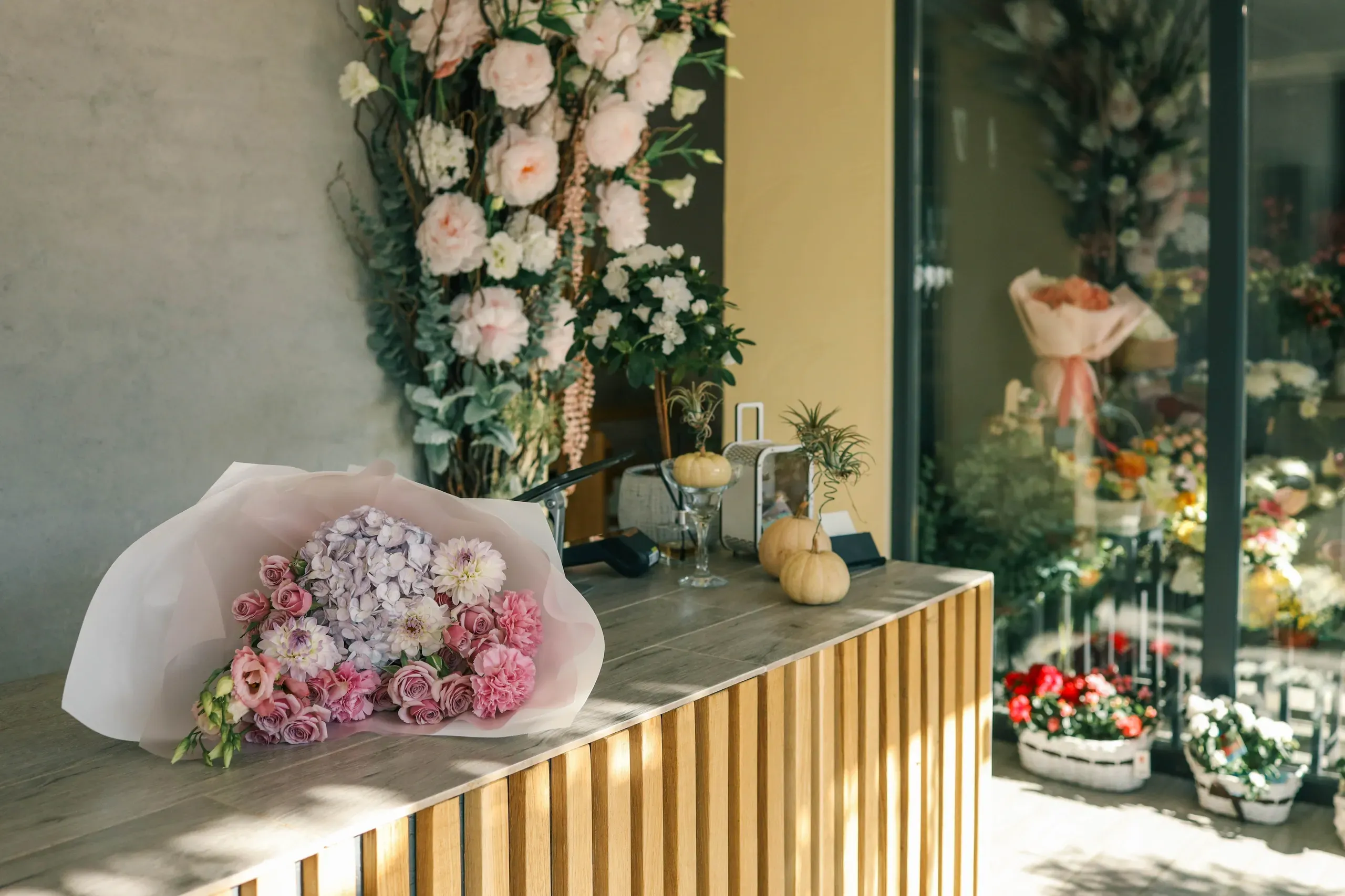 Wedding stationery display area with gold bar, pink florals, and romantic rose wall backdrop