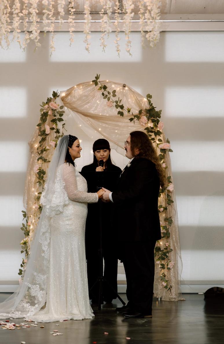 Wedding ceremony with couple and officiant under floral arch