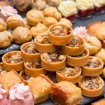 Assorted dessert tarts with nuts and pastries displayed on catering table