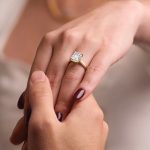 Emerald-cut diamond engagement ring with gold band worn on woman's hand