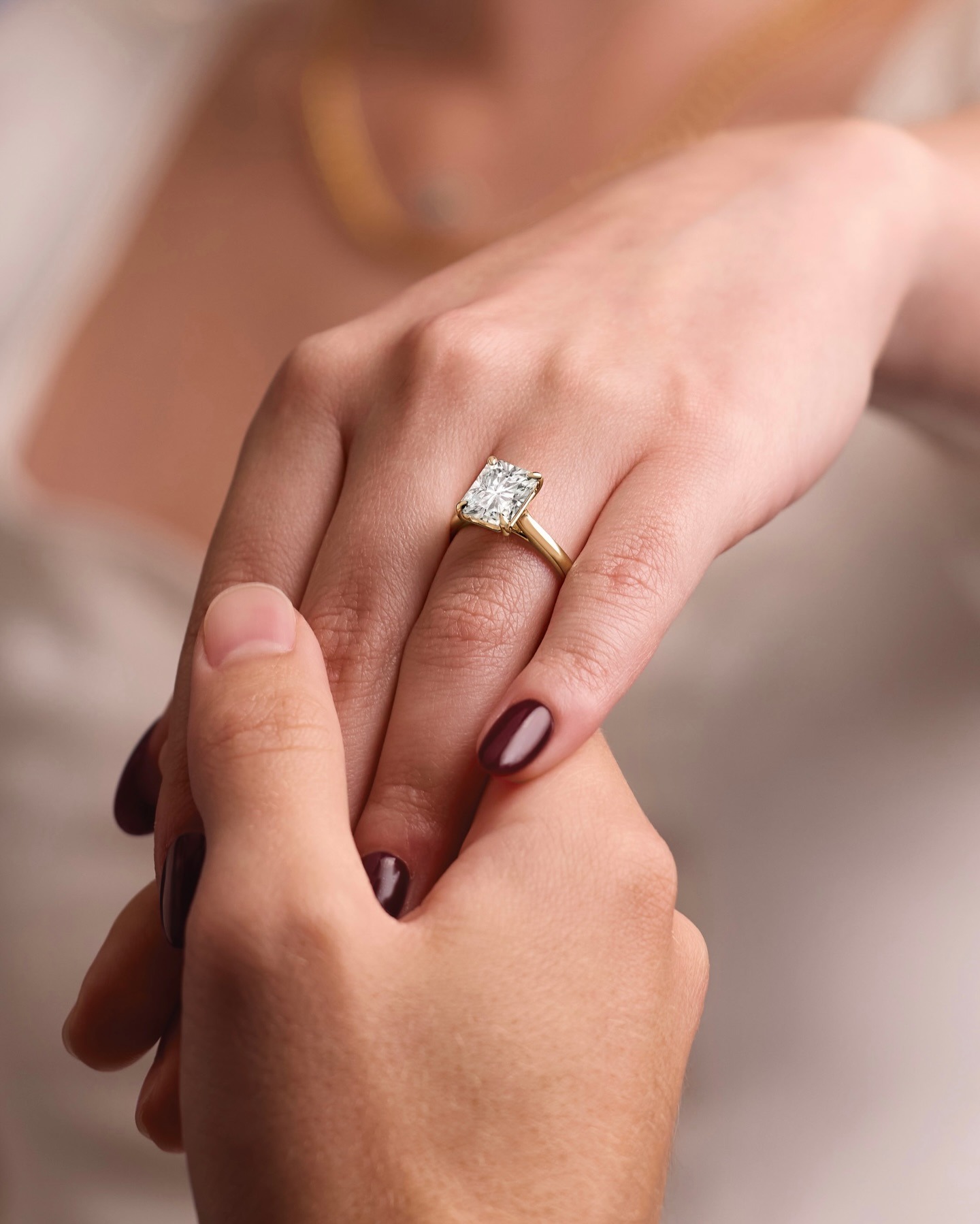 Emerald-cut diamond engagement ring with gold band worn on woman's hand