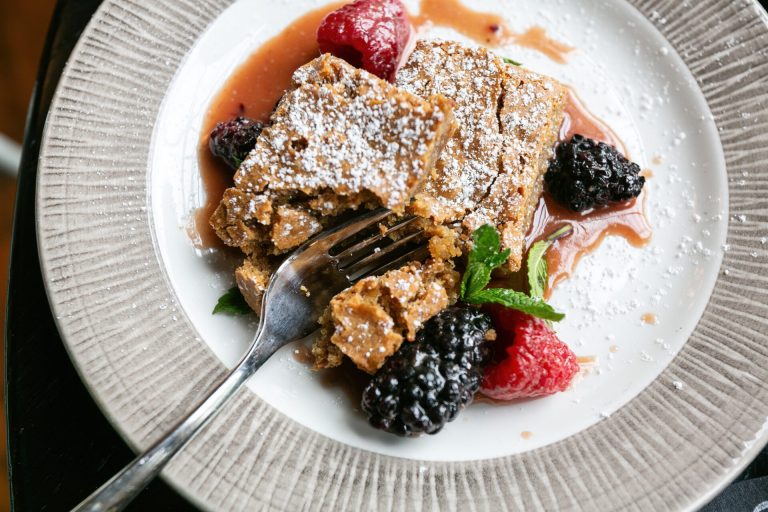 French toast dusted with powdered sugar, accompanied by fresh berries and mint on white plate