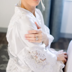 Bride in white lace robe posing during boudoir session