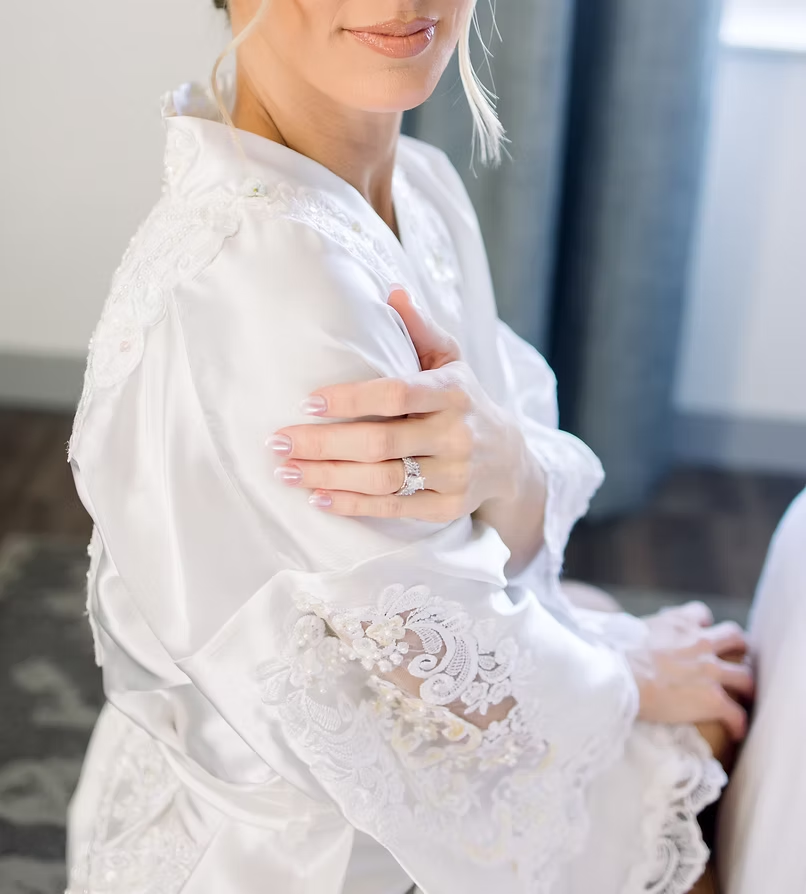Bride in white lace robe posing during boudoir session