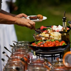 Professional wedding catering setup with tiered serving bowls of fresh ingredients and appetizers at outdoor venue